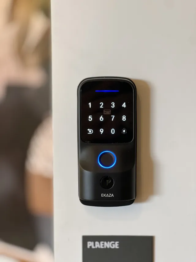 Fechadura digital preta com teclado iluminado instalada em porta clara